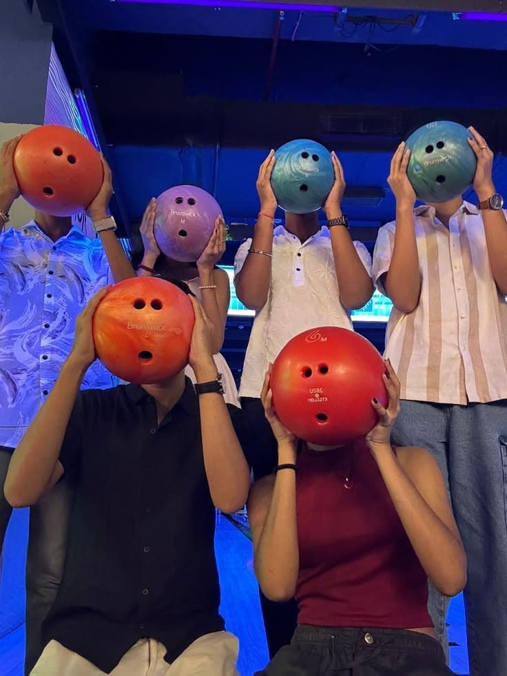 Friends holding bowling balls up to their faces