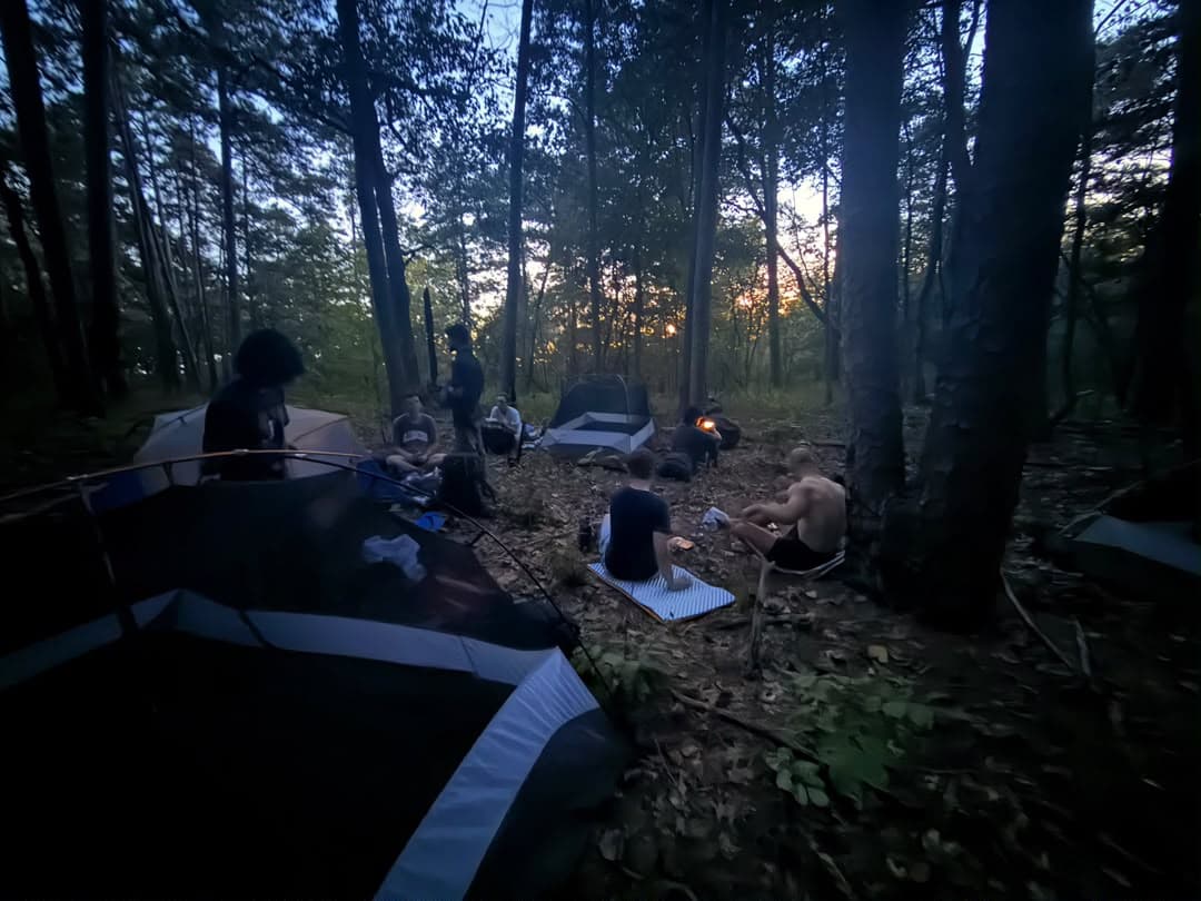 A group gathered around a campsite at dusk